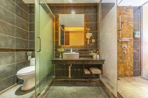 A modern bathroom with a glass shower enclosure, a built-in sink, and a toilet. - Jiahua Business Hotel (Guangzhou North Railway Station Huacheng Road Subway Station) (Guangzhou)