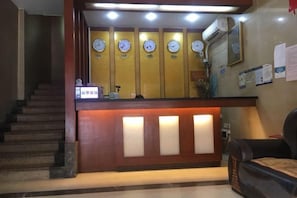 A reception area with a wooden counter, multiple clocks, and a staircase.
