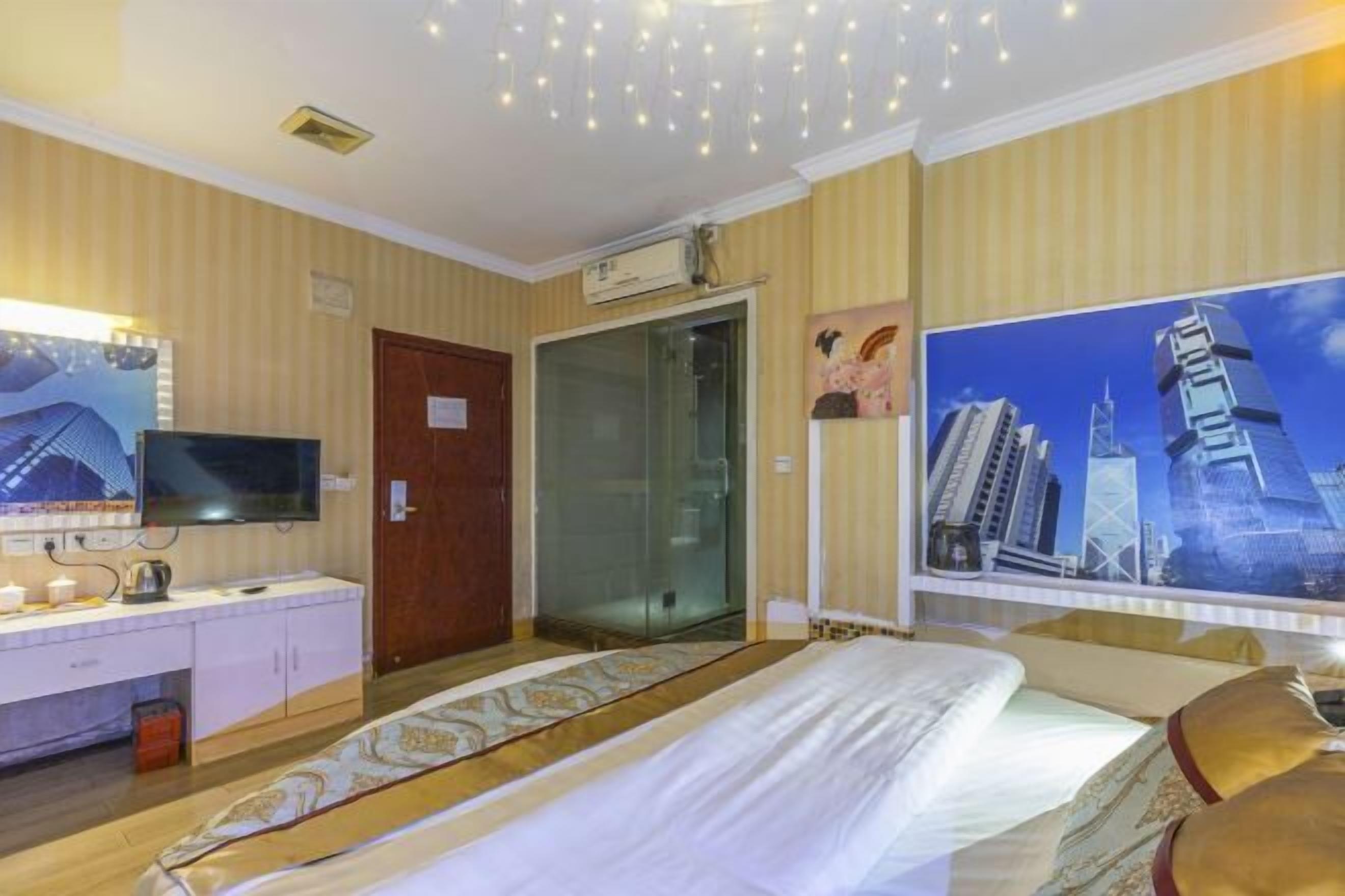 Quarto de hotel com cama, escrivaninha com televisão, chuveiro e vista para a cidade.