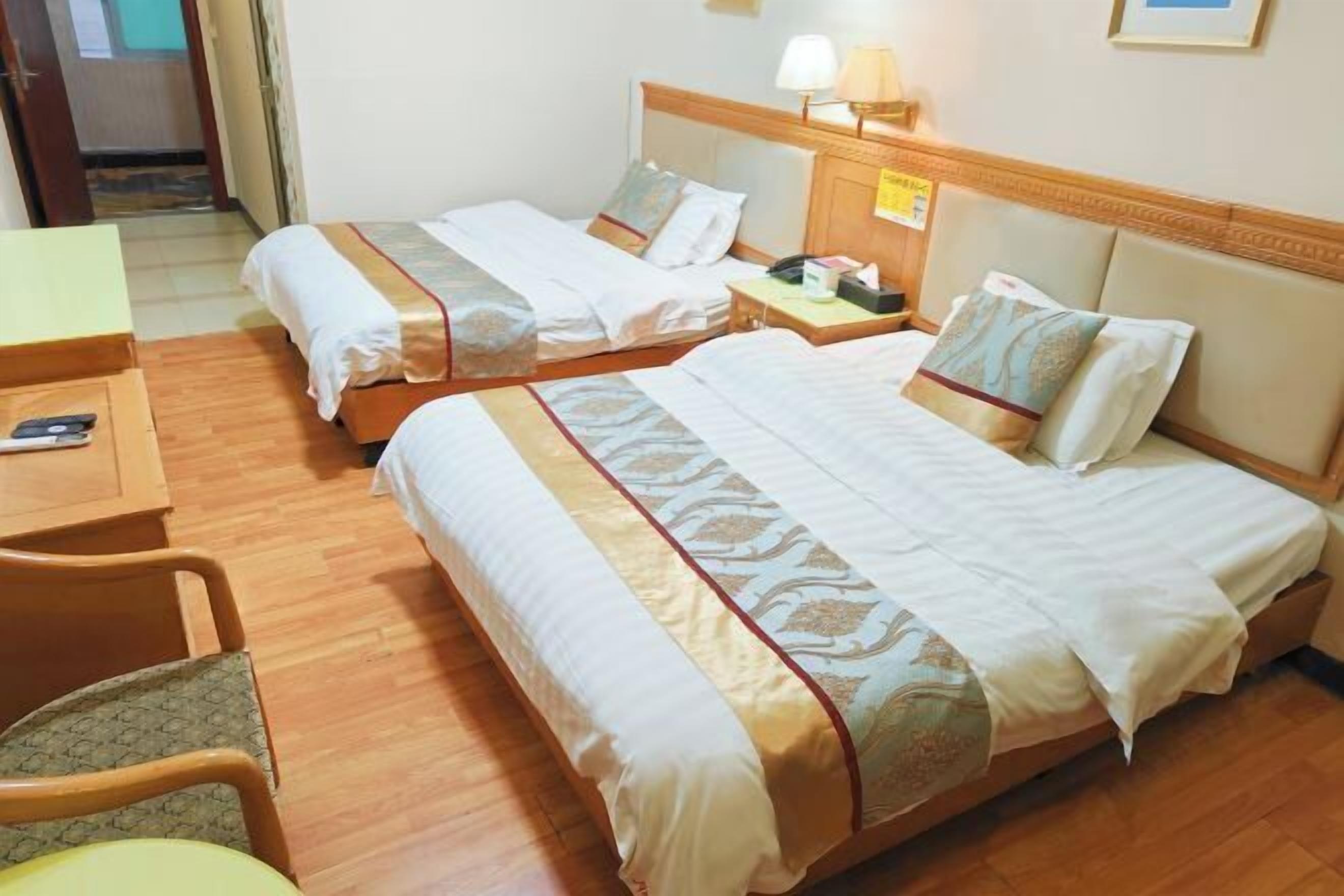 A hotel room with two beds, a desk, and a chair.