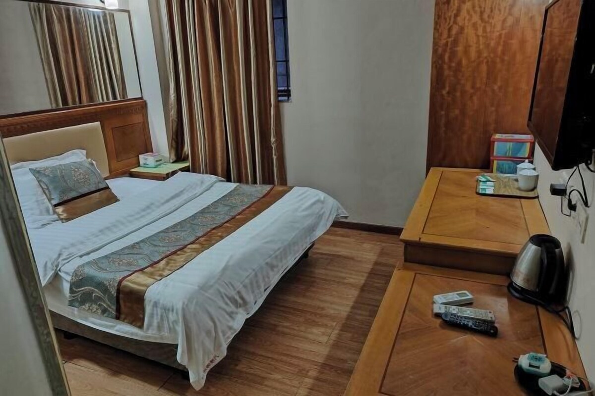 A hotel room with a bed, bedside table, TV, and a small seating area.