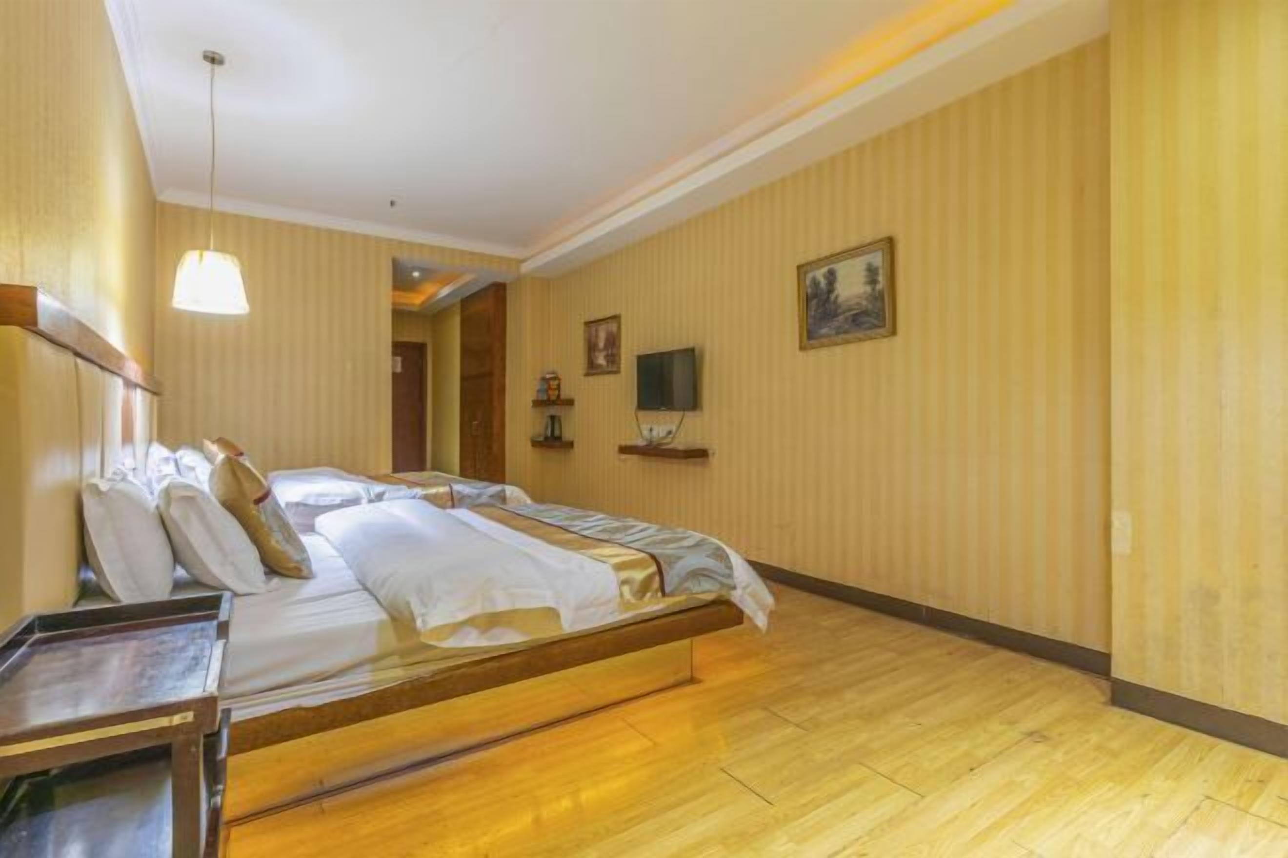 Una habitación de hotel con una cama de madera, una mesita de noche, un televisor y un cuadro en la pared.