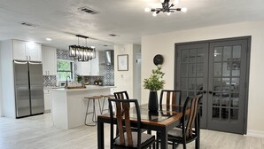 Una cucina moderna con isola centrale, elettrodomestici in acciaio inossidabile e zona pranzo con tavolo in vetro e sedie in legno.