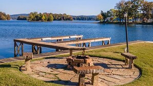 Un parc a la vora d'un llac amb taules de pícnic i una xemeneia de pedra.
