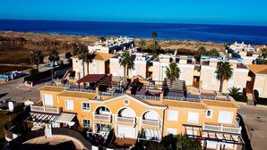 Un área residencial costera con varios edificios de dos pisos, algunos con balcones, y una vista despejada del océano.