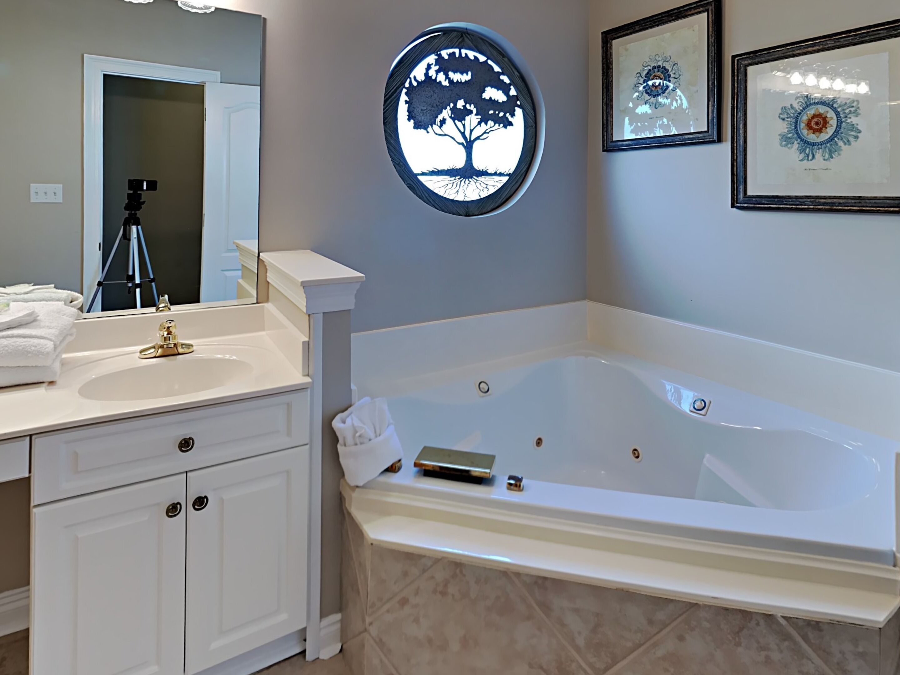 A bathroom with a white vanity, a large bathtub, and a mirror.