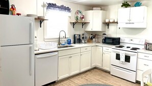Una cocina compacta con gabinetes blancos, un refrigerador, un microondas y una estufa.