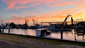 Un puerto deportivo al atardecer con barcos amarrados y grúas al fondo.
