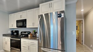A modern kitchen with white cabinetry, stainless steel appliances, and a granite countertop.