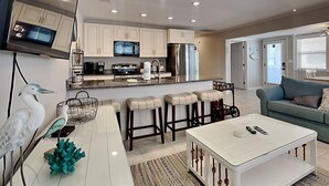 A modern kitchen with white cabinets, stainless steel appliances, and a central island with bar stools.