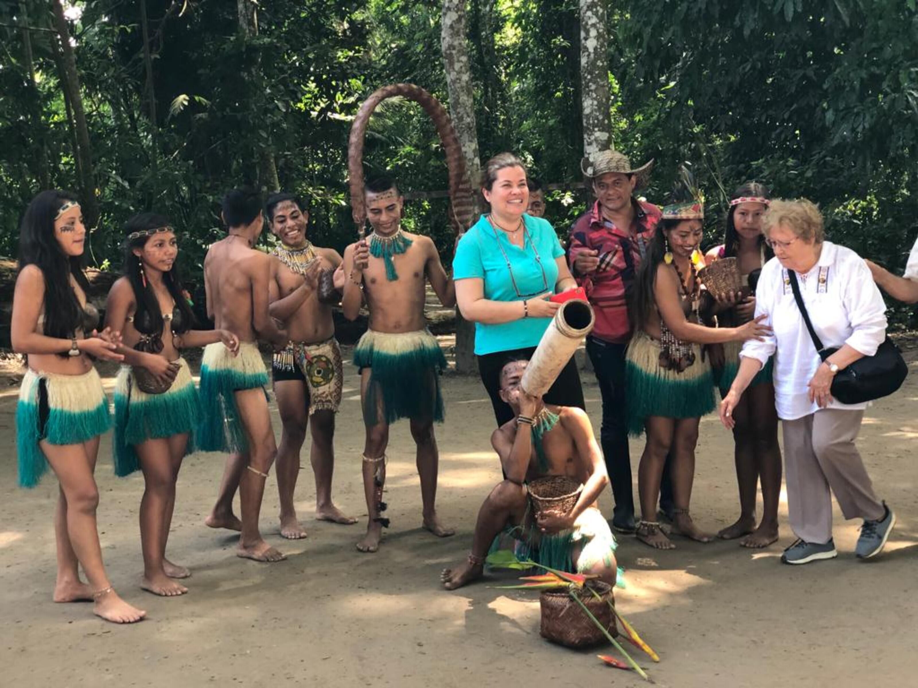 Un grupo de personas vestidas con atuendo tradicional, de pie al aire libre, con árboles de fondo.