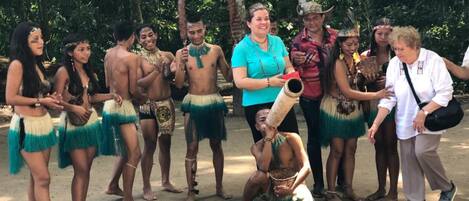 A group of people in traditional attire, standing outdoors with trees in the background.