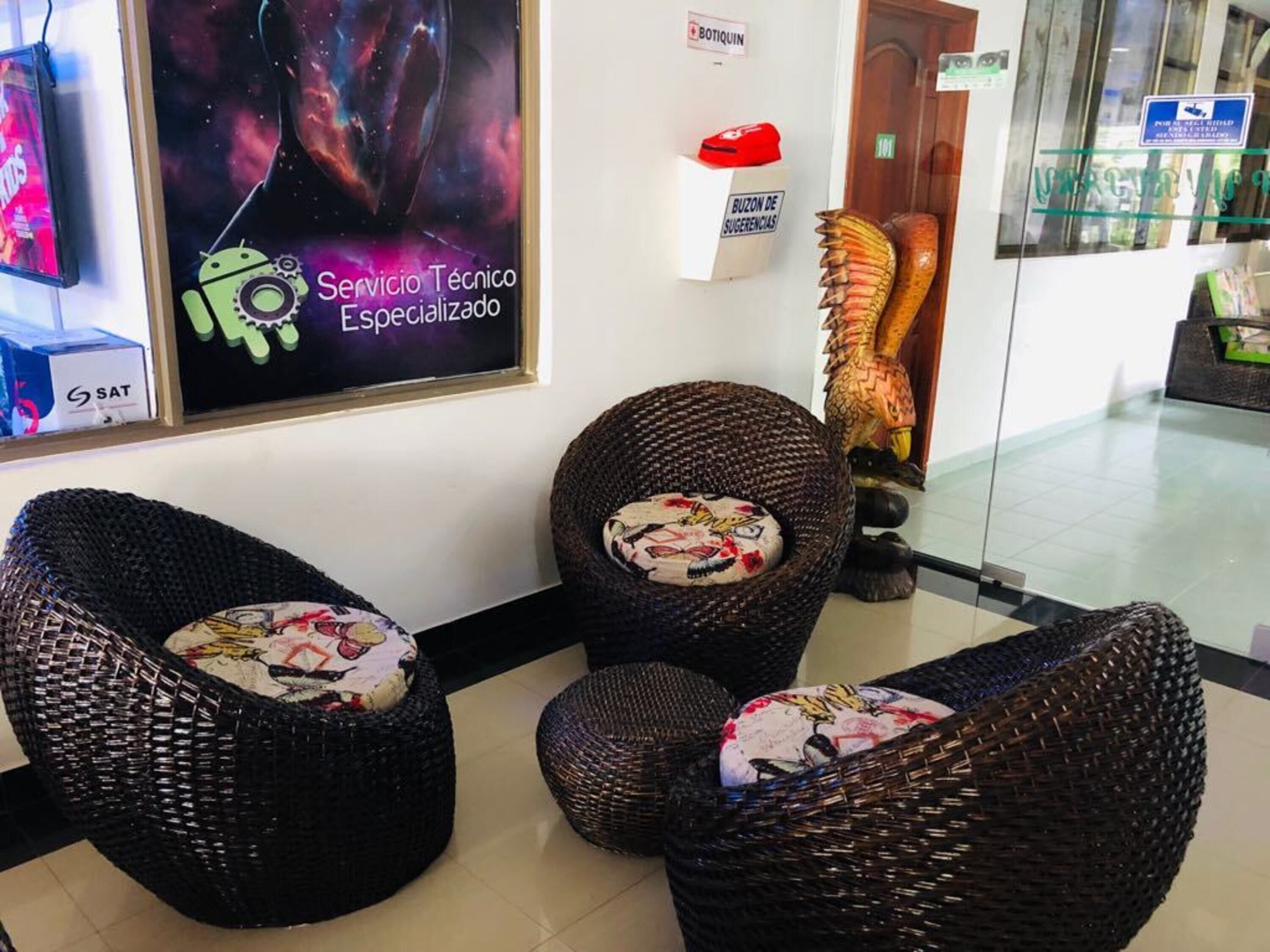 A lobby with wicker chairs, a poster, and a sign indicating a service area.