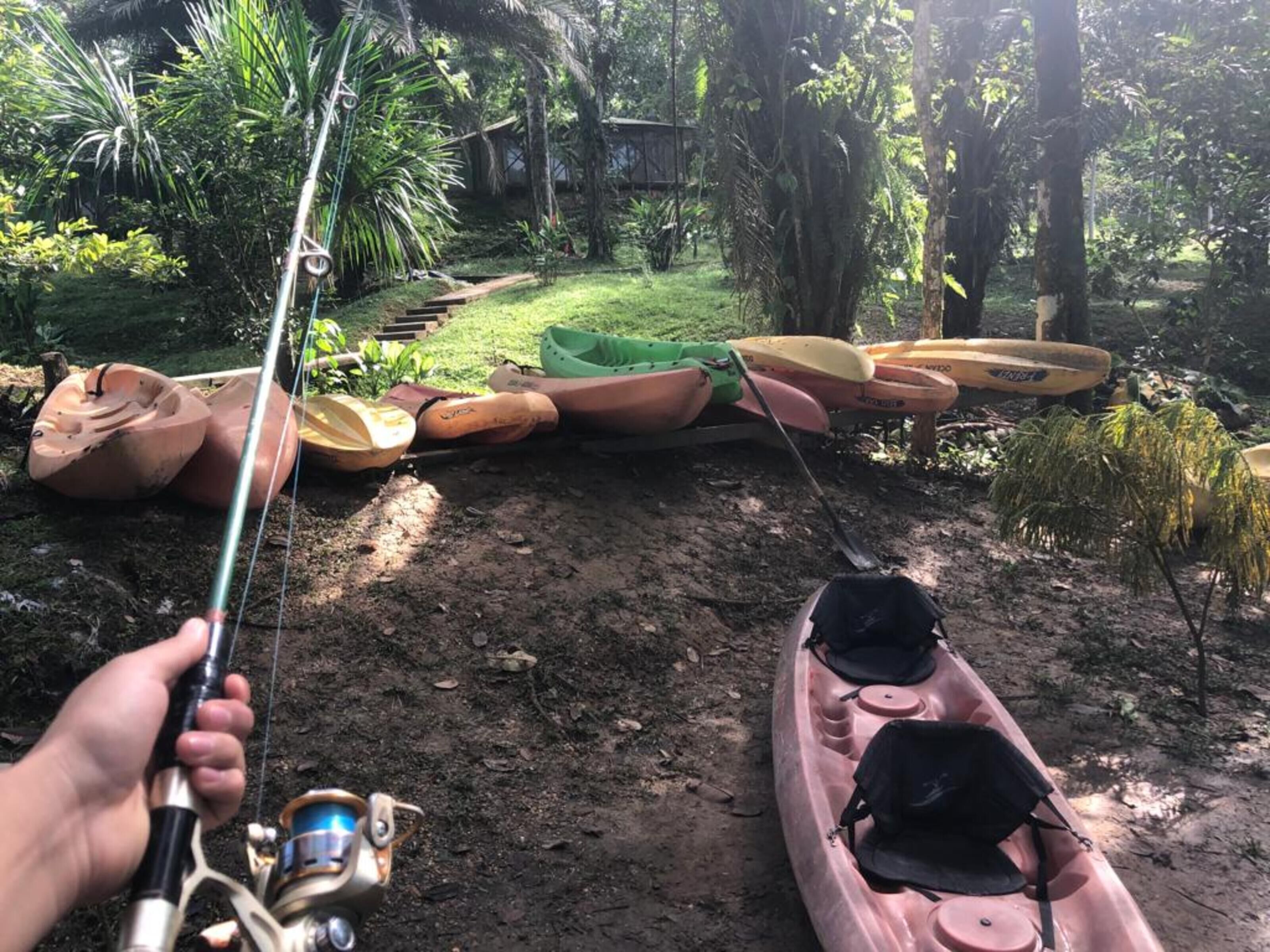 Una caña de pescar con carrete y un kayak rosa con una bolsa negra.
