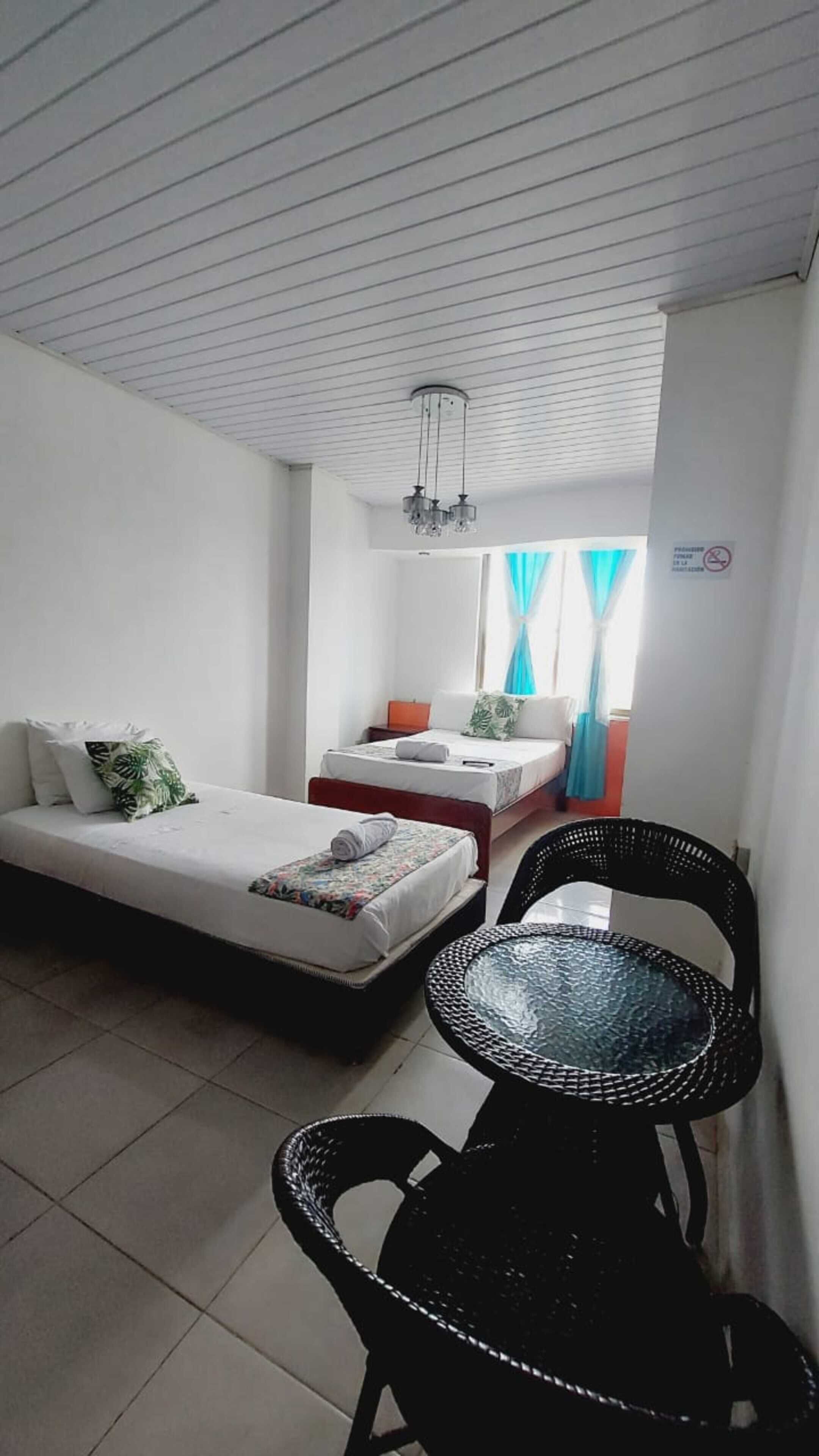 A room with two beds, a small table, and a chair.