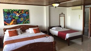 A hotel room with two wooden beds, a large abstract painting on the wall, a ceiling fan, and a sliding glass door. - Hotel Yurupary (Leticia)