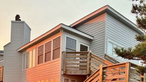 Una casa de dos pisos con una escalera de madera que sube a una terraza.