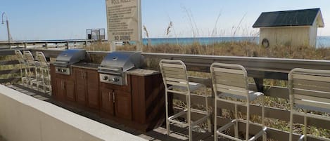 Área de churrasco externa com cadeiras e placa indicando as regras da piscina e proibição de mergulho.