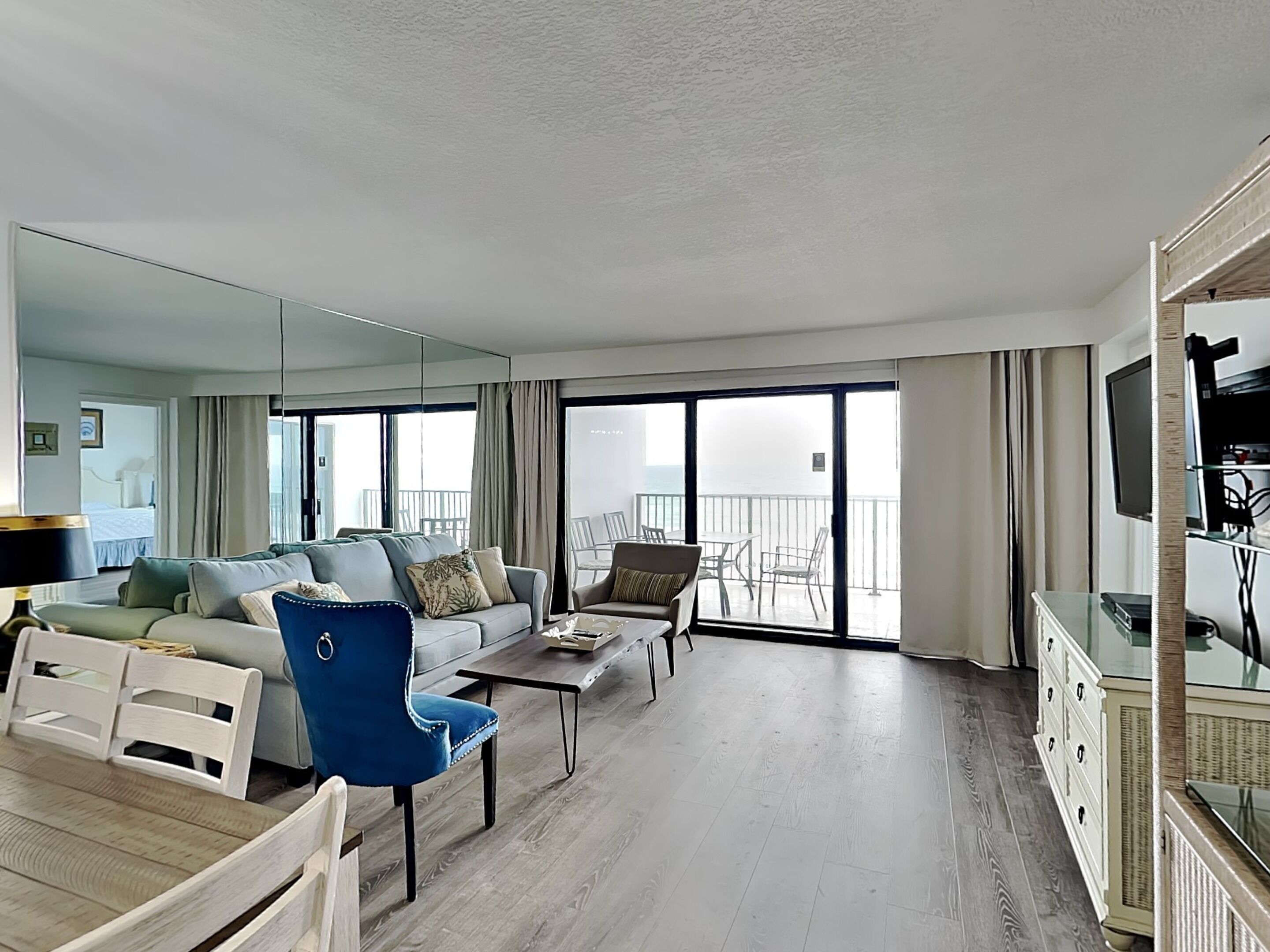 Ein modernes Hotelzimmer mit Wohnbereich, einem Balkon mit Sitzmöbeln und einem Fernseher.