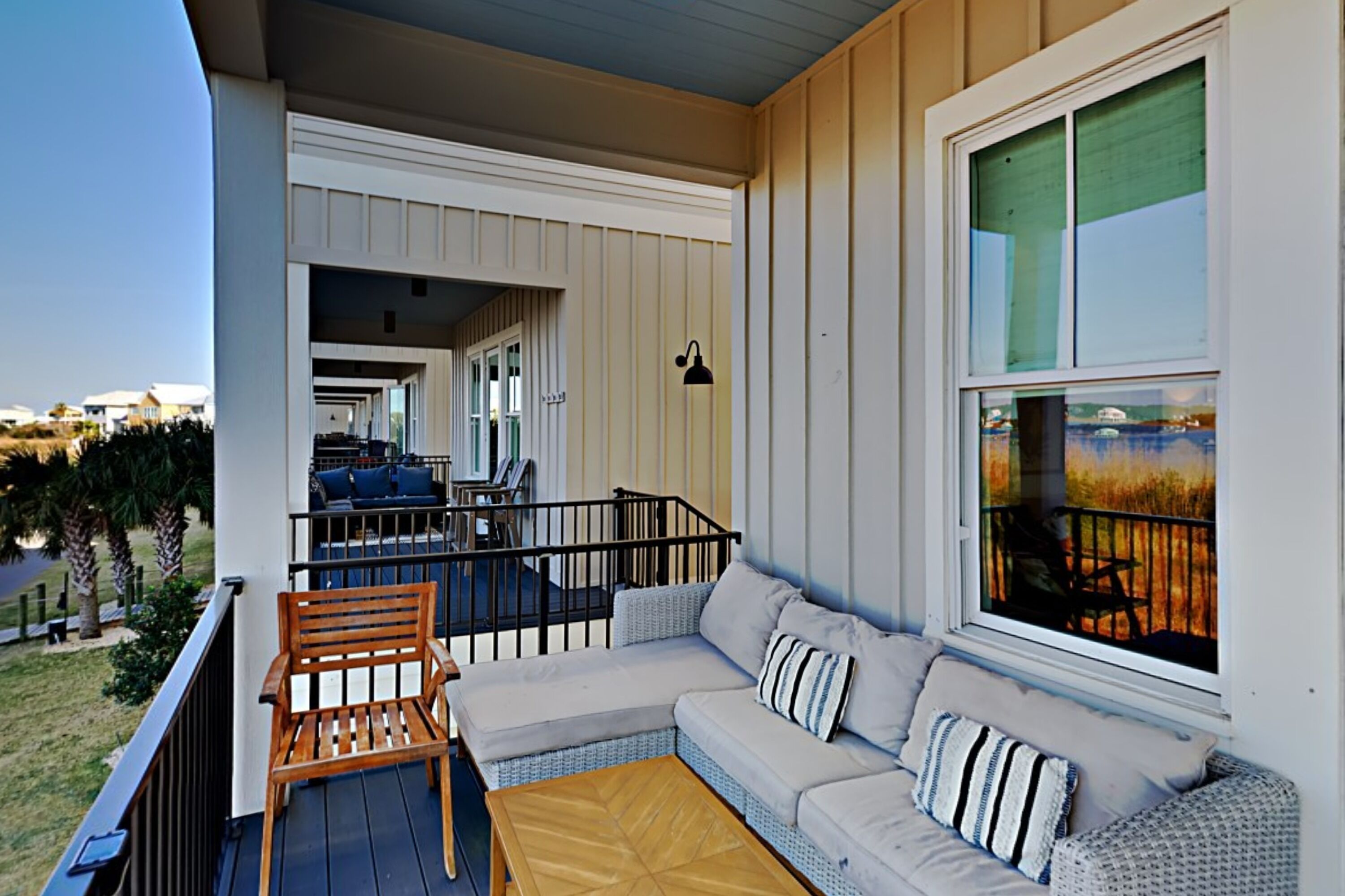 A balcony with a wooden chair, a sofa with cushions, and a view of the landscape.