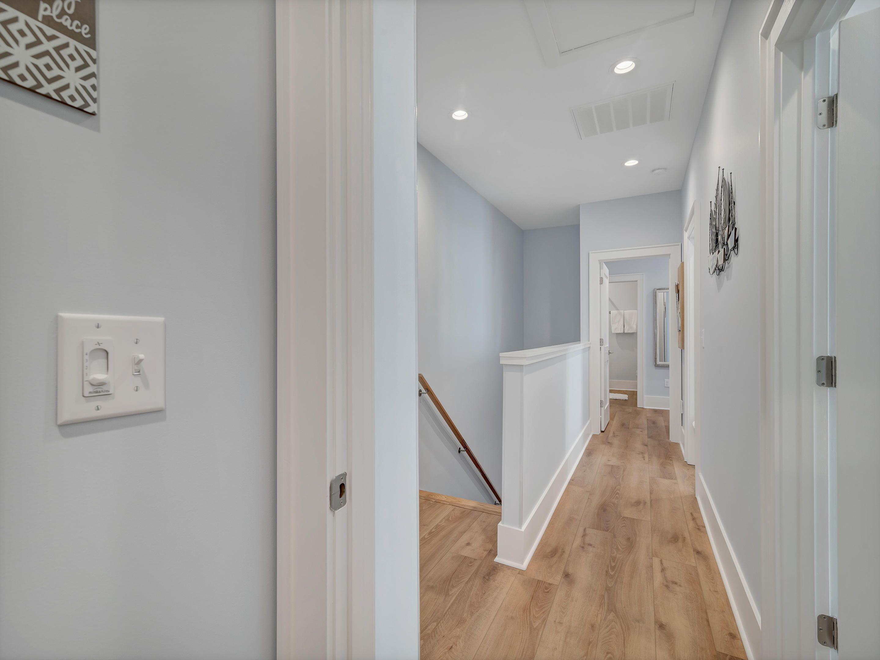 A hallway with light blue walls, wooden flooring, and white doors.