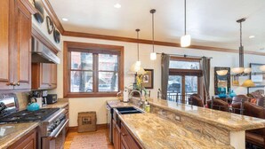 A kitchen with wooden cabinets, a granite countertop, and a large island. - Ajax Peak Views, Townhome on Sunnyside of Historic Downtown Telluride (Telluride)