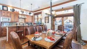 A dining area with a wooden table, leather chairs, and a view through large windows. - Ajax Peak Views, Townhome on Sunnyside of Historic Downtown Telluride (Telluride)