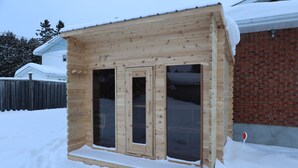 Una cabaña de madera con dos ventanas grandes y un pequeño porche.
