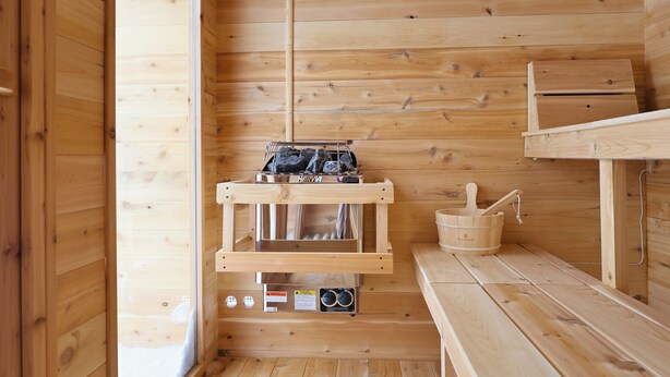Un vestíbulo de sauna de madera con un banco de sauna, un banco de madera y un calentador de sauna.