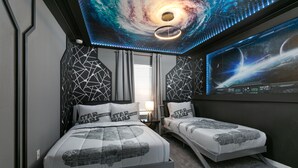 A bedroom with a galaxy-themed ceiling, two beds with Star Wars bedding, and a wall-mounted TV displaying a space scene. - Stylish 4BR Townhome, Themed Rooms, Private Pool. Near Disney! (Kissimmee)