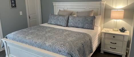 A bedroom with a bed, nightstand, and wall art.