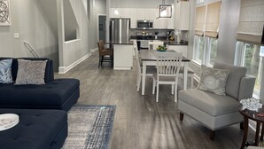 Una cocina moderna con armarios blancos, electrodomésticos de acero inoxidable y un comedor con mesa y sillas.