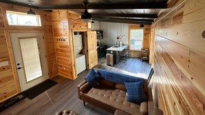 Een gezellig cabin interieur met een zithoek, een bank en een poef, een keuken met een centraal eiland en een eethoek.