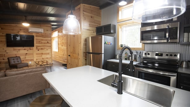 A modern kitchen with stainless steel appliances, a wooden interior, and a large island with a sink. - SUADA-Superior ADA Cabin (Park City)