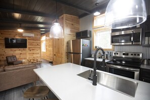 Eine moderne Küche mit Edelstahlgeräten, Holzvertäfelung und einer großen Kochinsel mit Spüle.