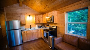 A wooden cabin interior with a kitchen featuring a refrigerator, stove, and microwave. - The Maple Retreat-Log Cabin (Park City)