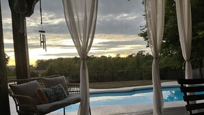 A wooden deck with a pool, a cushioned outdoor seating area, and a view of a forested area. - Private Pool, 1st Floor Bedroom, Hershey Park, Ski Roundtop, Yellow Breeches. (Mechanicsburg)