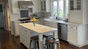 A modern kitchen with white cabinetry, a central island with stools, pendant lighting, and a view to the outside. - Private Pool, 1st Floor Bedroom, Hershey Park, Ski Roundtop, Yellow Breeches. (Mechanicsburg)