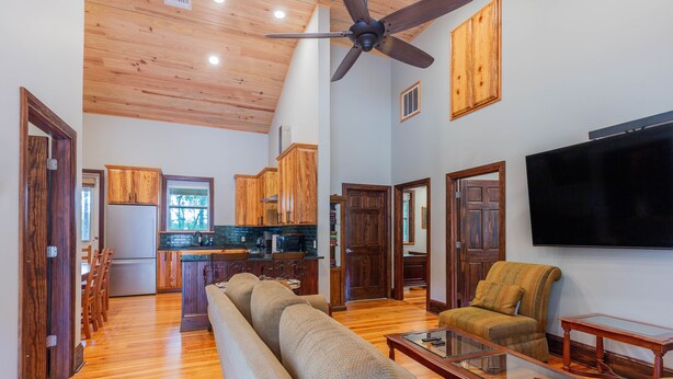 A spacious living room with a large sofa, a television, and wooden flooring.