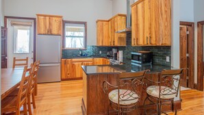 A kitchen with wooden cabinets, a central island, and a dining area with chairs.