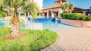 A swimming pool with palm trees, a brick pathway, and a building with balconies. - Seachase #1501W by Southern Vacation Rentals (Orange Beach)