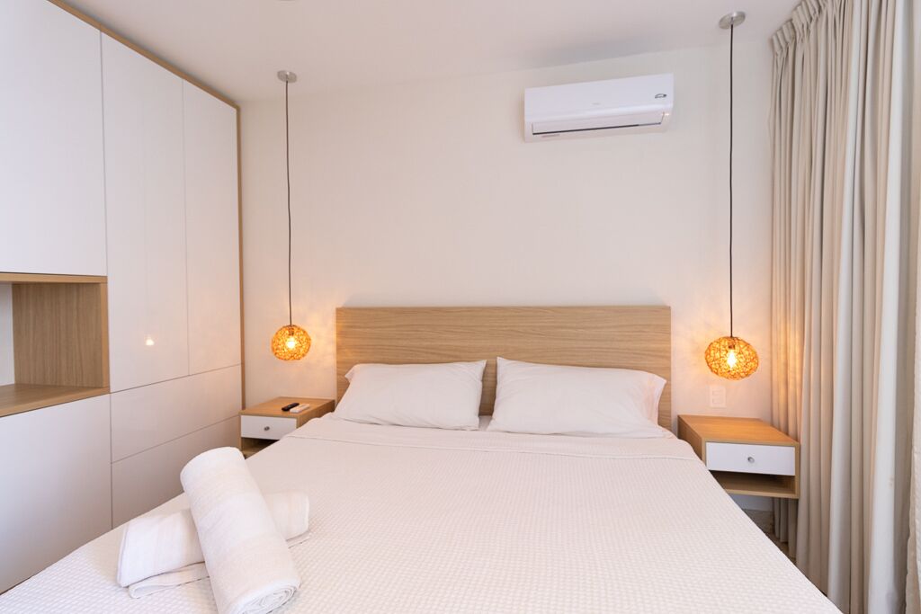 Ein Hotelzimmer mit einem großen Bett, zwei Nachttischen, einer Klimaanlage und einer Pendelleuchte.