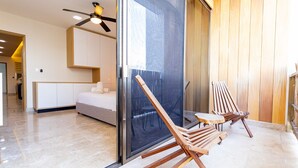 A modern room with a bed, a glass door, and two wooden chairs. - Gaia 1-BR Suite (Tulum)