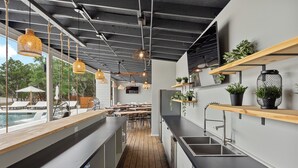 A modern kitchen with wooden countertops, a built-in sink, and hanging pendant lights. - Boutique Resort for Weddings & Retreats w/ Pool, Wellness, Pickleball, & More! (Wimberley)