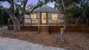A yurt with a wooden exterior, a central door, and a staircase leading to the entrance. - Boutique Resort for Weddings & Retreats w/ Pool, Wellness, Pickleball, & More! (Wimberley)