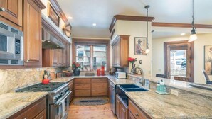 A kitchen with wooden cabinets, a granite countertop, stainless steel appliances, and a window overlooking the backyard. - One of Three Lovely, Sunnyside Town of Telluride Homes-Select 1, 2, or All 3! (Telluride)