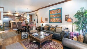 A spacious living room with a leather sofa, a coffee table, and a dining area with chairs and a table. - One of Three Lovely, Sunnyside Town of Telluride Homes-Select 1, 2, or All 3! (Telluride)