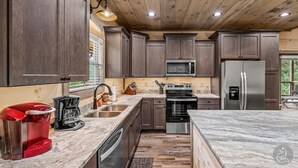 Une cuisine moderne avec des meubles en bois foncé, des appareils électroménagers en acier inoxydable et un plan de travail en marbre.