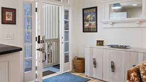 Una habitación con una puerta que da a un balcón, un armario con un plato decorativo y un póster enmarcado en la pared.