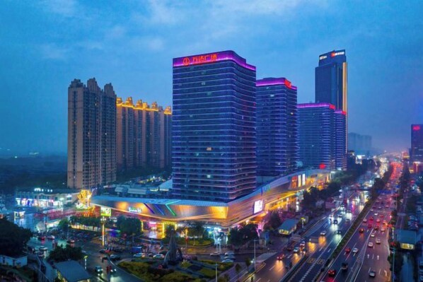 A multi-story hotel with a modern design, featuring a prominent entrance and a busy street in the background. - Jianglong Hotel (Dongguan Houjie Wanda Plaza) (Dongguan)